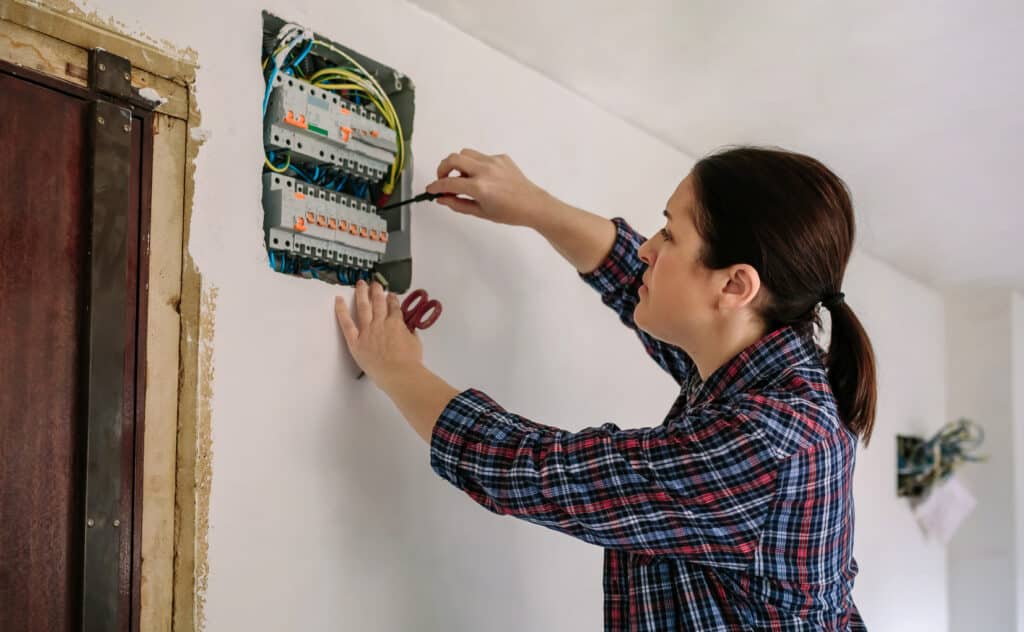 Female electrician working on the distribution panel of a house