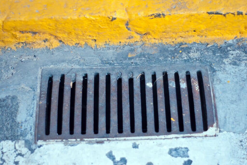 Close-up shot of a concrete floor, featuring a stainless steel drain pipe on it