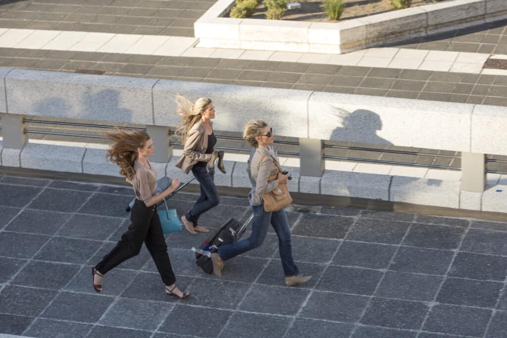 Three adult women running across elevated walkway