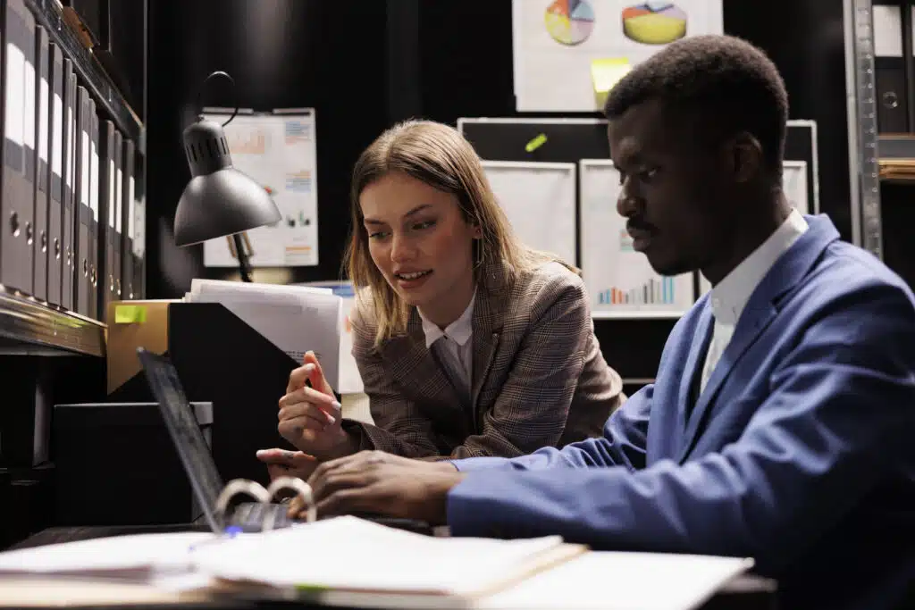 Diverse bookkeepers analyzing bureaucracy record, looking at administrative documents in corporate depository. Businesspeople reading accountancy report, discovering management research files