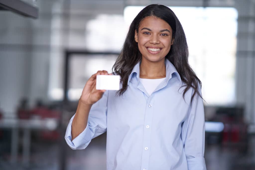 Portrait of smiling woman holding and showing to camera empty card of worker. Management and company