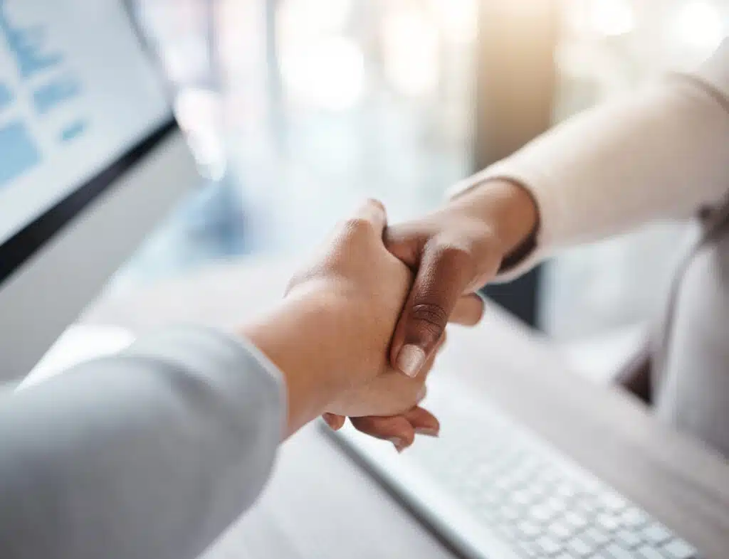Closeup of two businesswomen shaking hands over a desk during a meeting in an office. Colleagues fi.