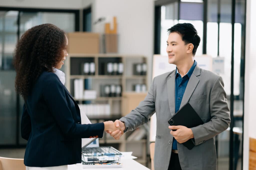 Two confident business man shaking hands during a meeting in the office, success, dealing, greeting and partner in sun light