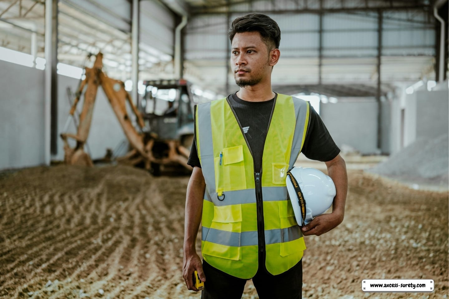 A helmeted construction worker stands.