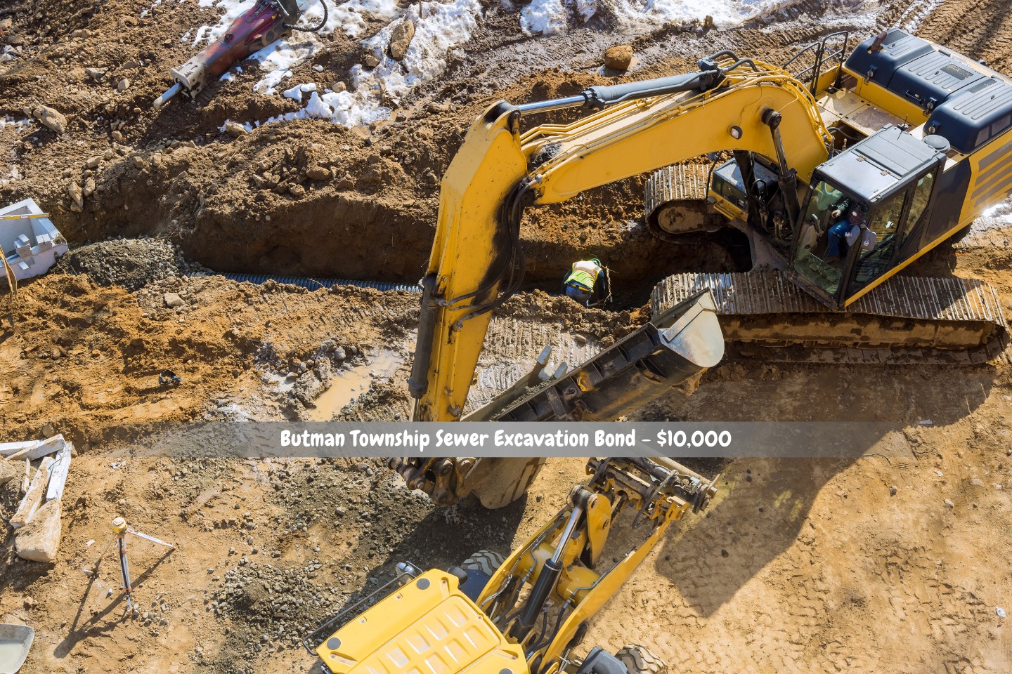 Butman Township Sewer Excavation Bond - $10,000 - At a construction site, an excavator digs a trench to install sewer pipes.