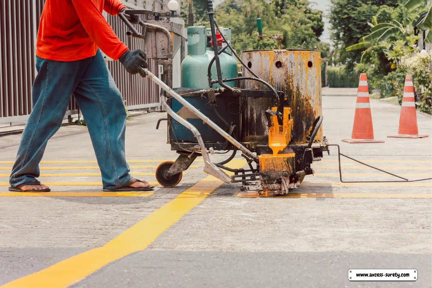 Traffic lines are painted on the asphalt road surface by road workers.