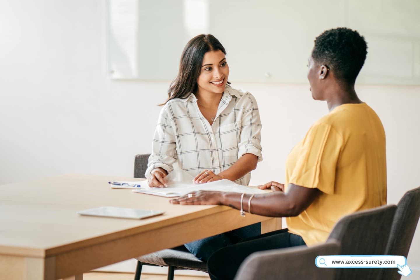 A collection agent is talking with their documents while seated at a table.