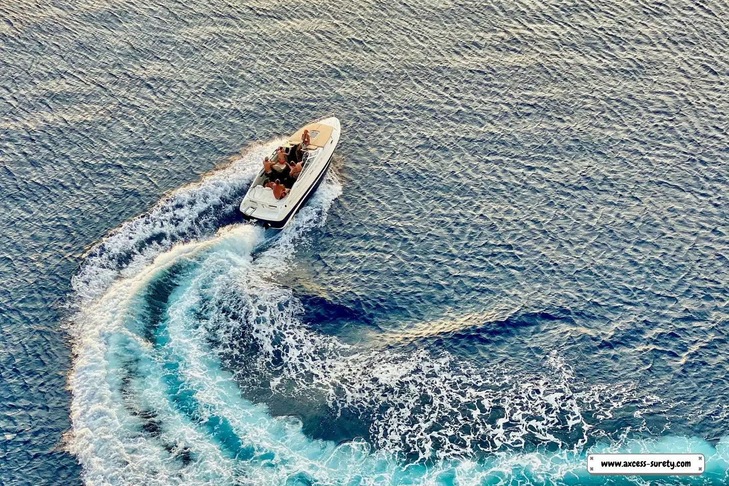 An aerial photograph of a speedboat with five passengers turning.