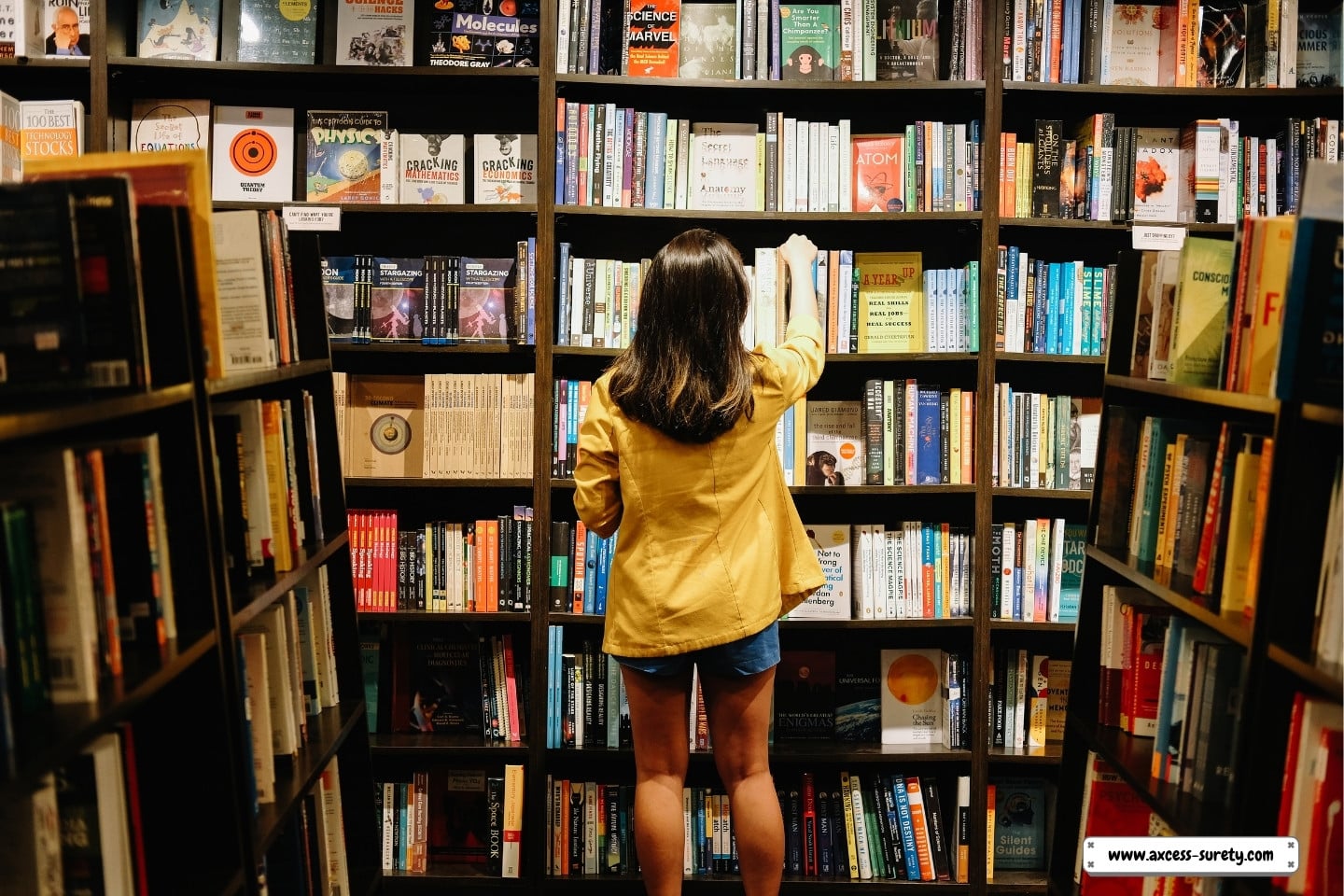 In the store, a woman is searching for books.