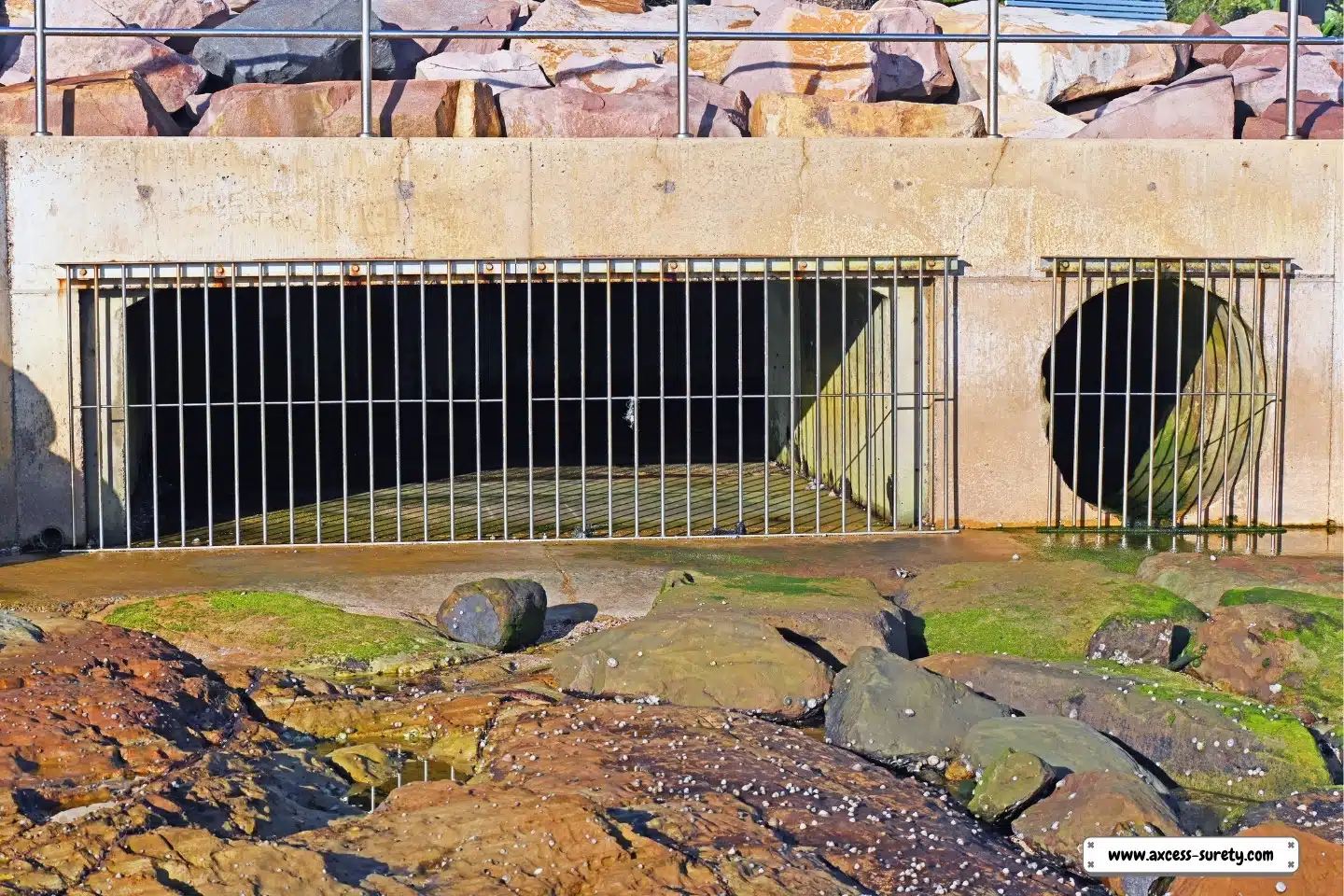At the shore is a sizable storm water outflow with stainless steel bars.