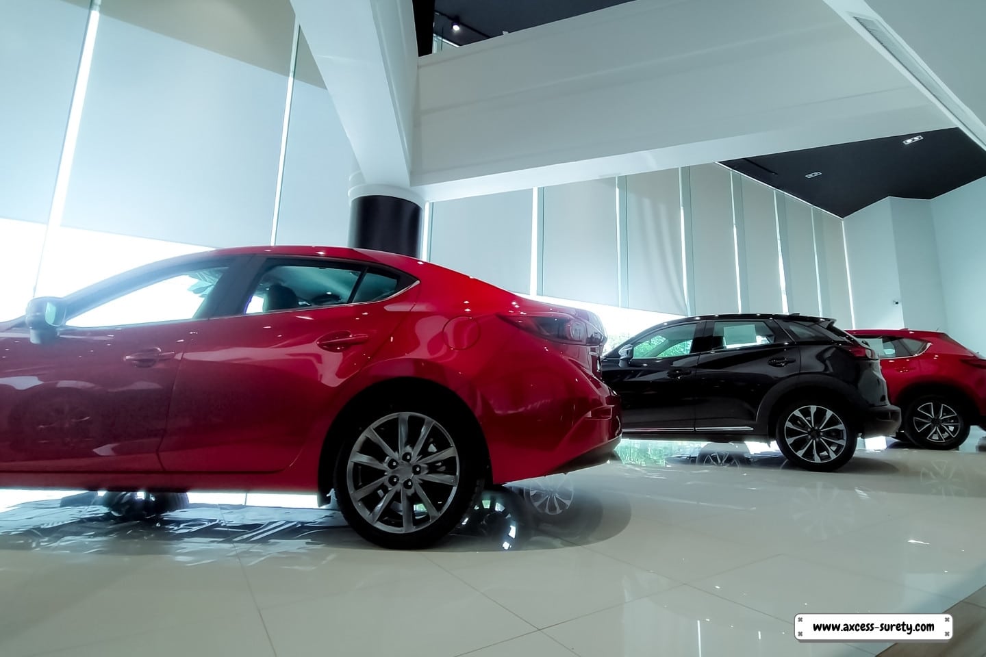 A red and black automobile waiting for new owners is parked in a contemporary dealership.