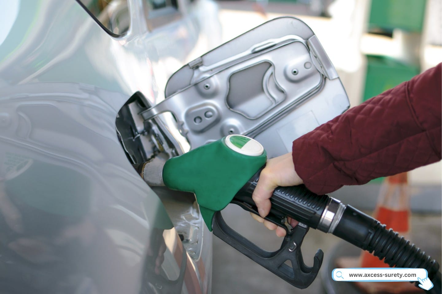 At the gas station, a woman is manually adding fuel to the automobile.