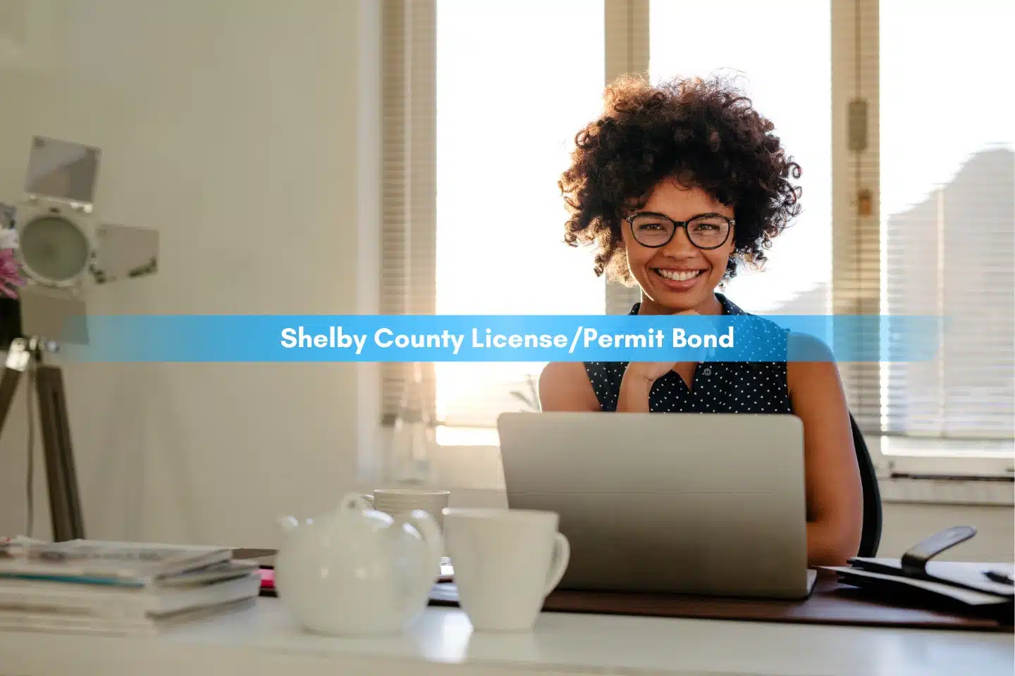Shelby County License/Permit Bond - Portrait of smiling young woman sitting at her desk with laptop.