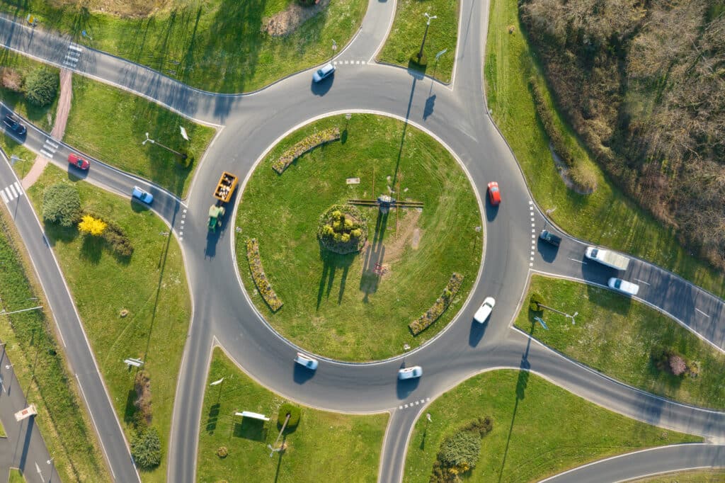 Aerial view of road roundabout intersection with moving heavy traffic. Urban circular transportation crossroads.