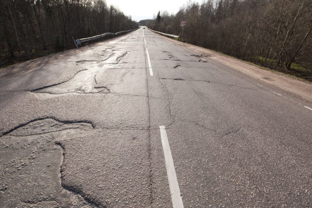 Bad quality road with potholes. Hole in asphalt. Pit, uAnsafe, hole road. Transportation, risk of movement by car