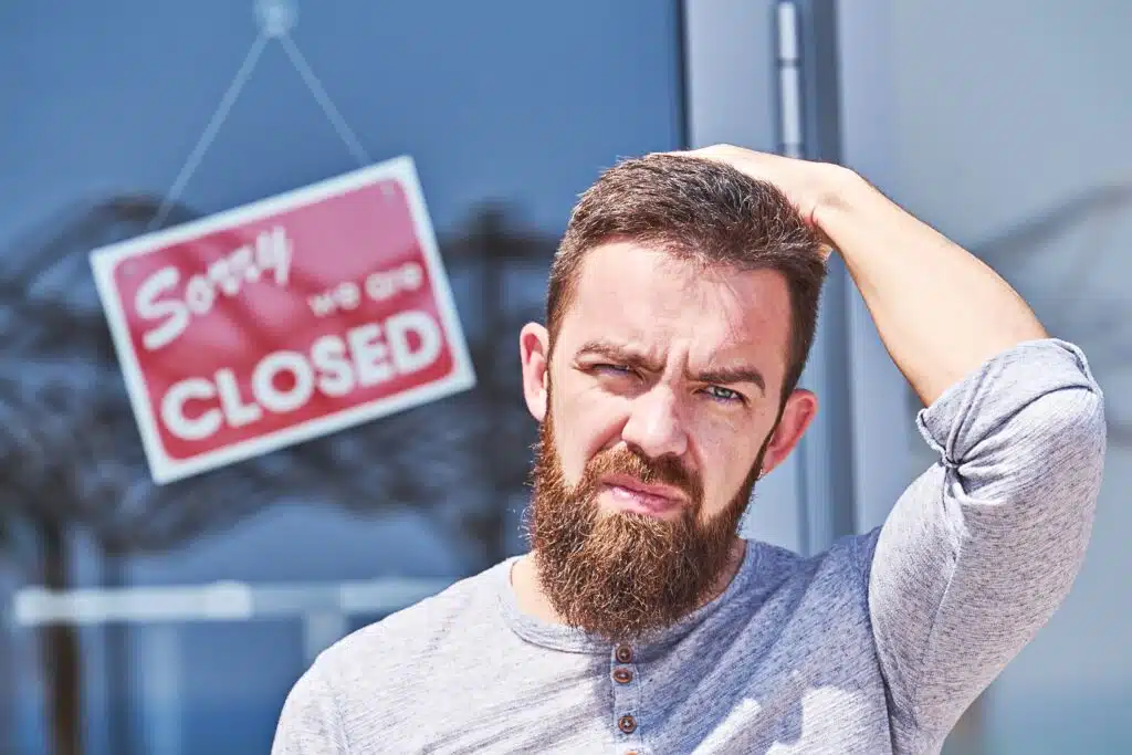 Closeup of bemused man near closed-door of office. Unemployment during coronavirus Covid-19 crisis, concept of job loss