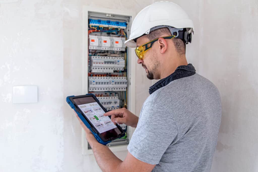 Man, an electrical technician working in a switchboard with fuses. Installation and connection of electrical equipment.