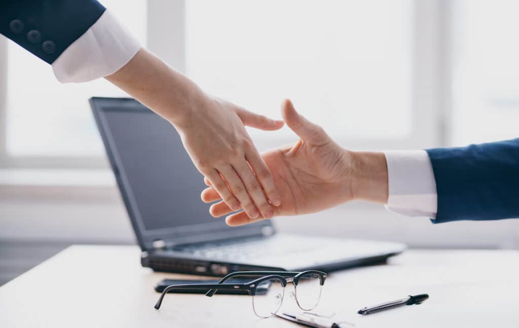 Handshake gesturing hands laptop office work window room. High quality photo