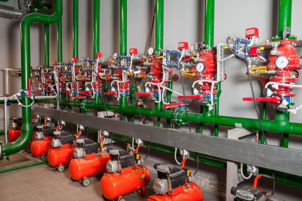 Industrial interior of water pump, valves, pressure gauges, motors inside engine room. Valve and pumps in an industrial room. Urban modern powerful pipelines and pumps, automatic control systems