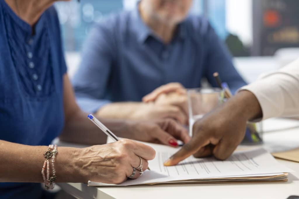 Middle aged woman signing retirement plan contract to secure the future income, investing money to cover family expenses. Senior people agreeing to life insurance policy in office.