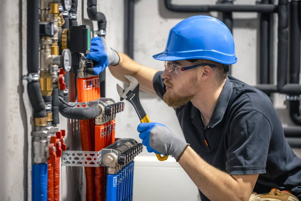 The technician checking the heating system in the boiler room. Adjusting heating valves in a residential building. A plumbing and heating technician works.