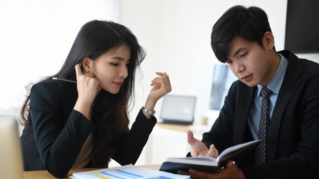 Two business colleagues working together in modern office and talking over business report.