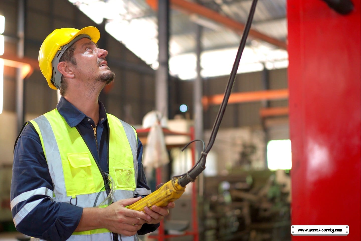 A technician in a factory operating a large crane.