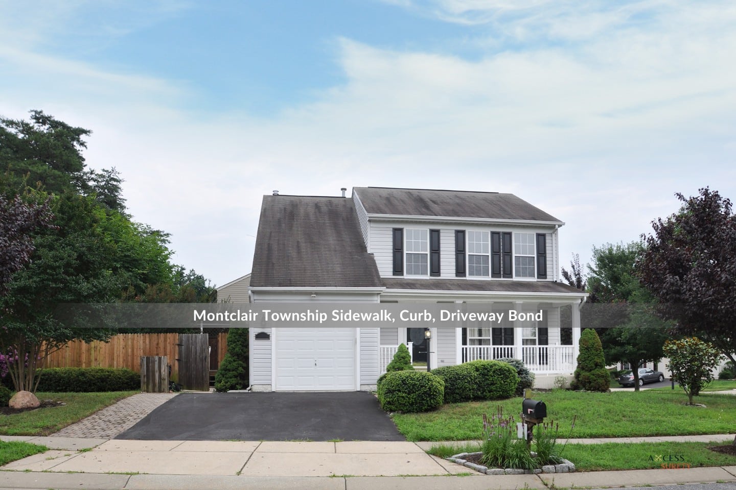 Montclair Township Sidewalk, Curb, Driveway Bond - A blacktop driveway mailbox with purple flowers in the front yard of a suburban home.