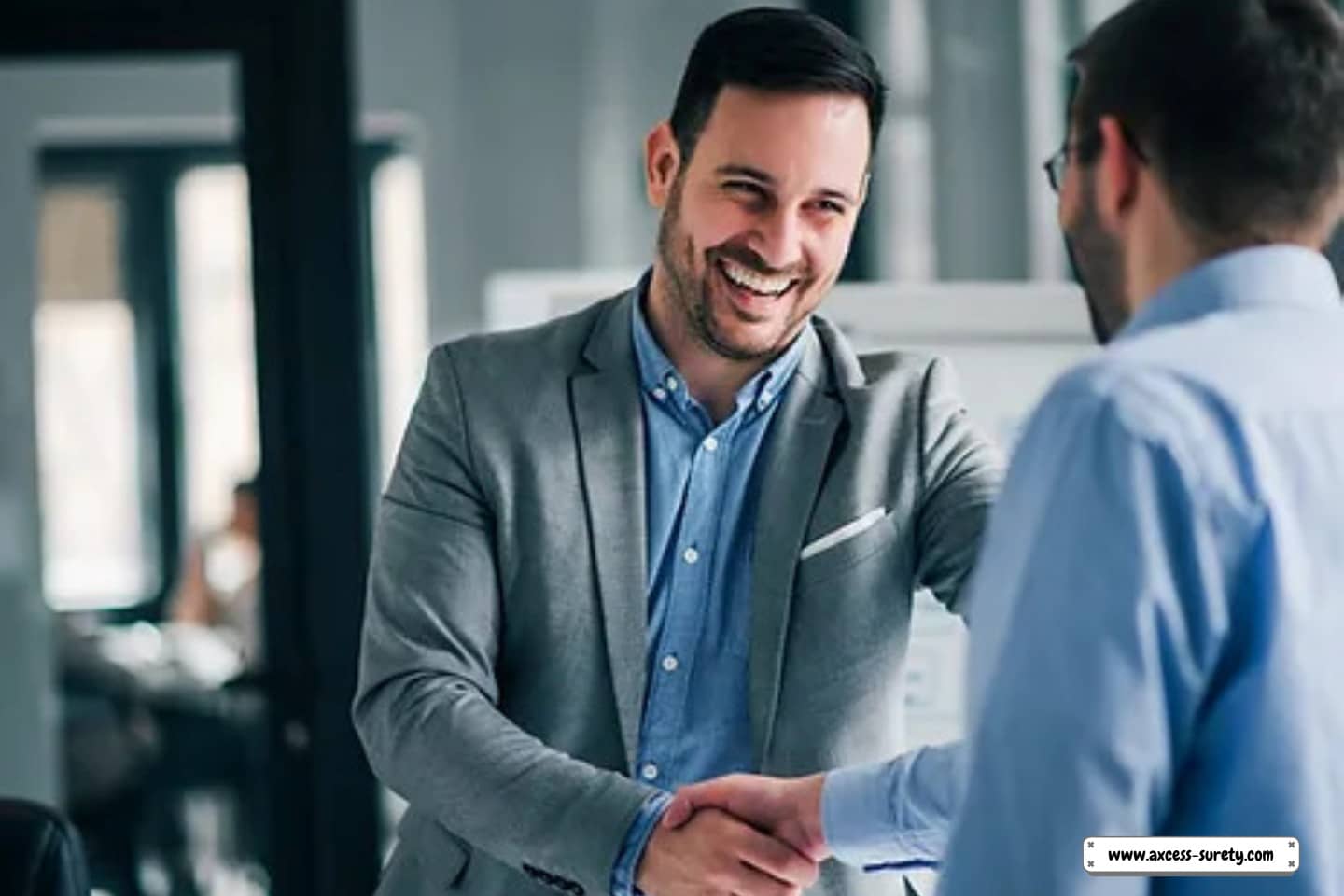 Two males in the office are making a deal and shaking hands.
