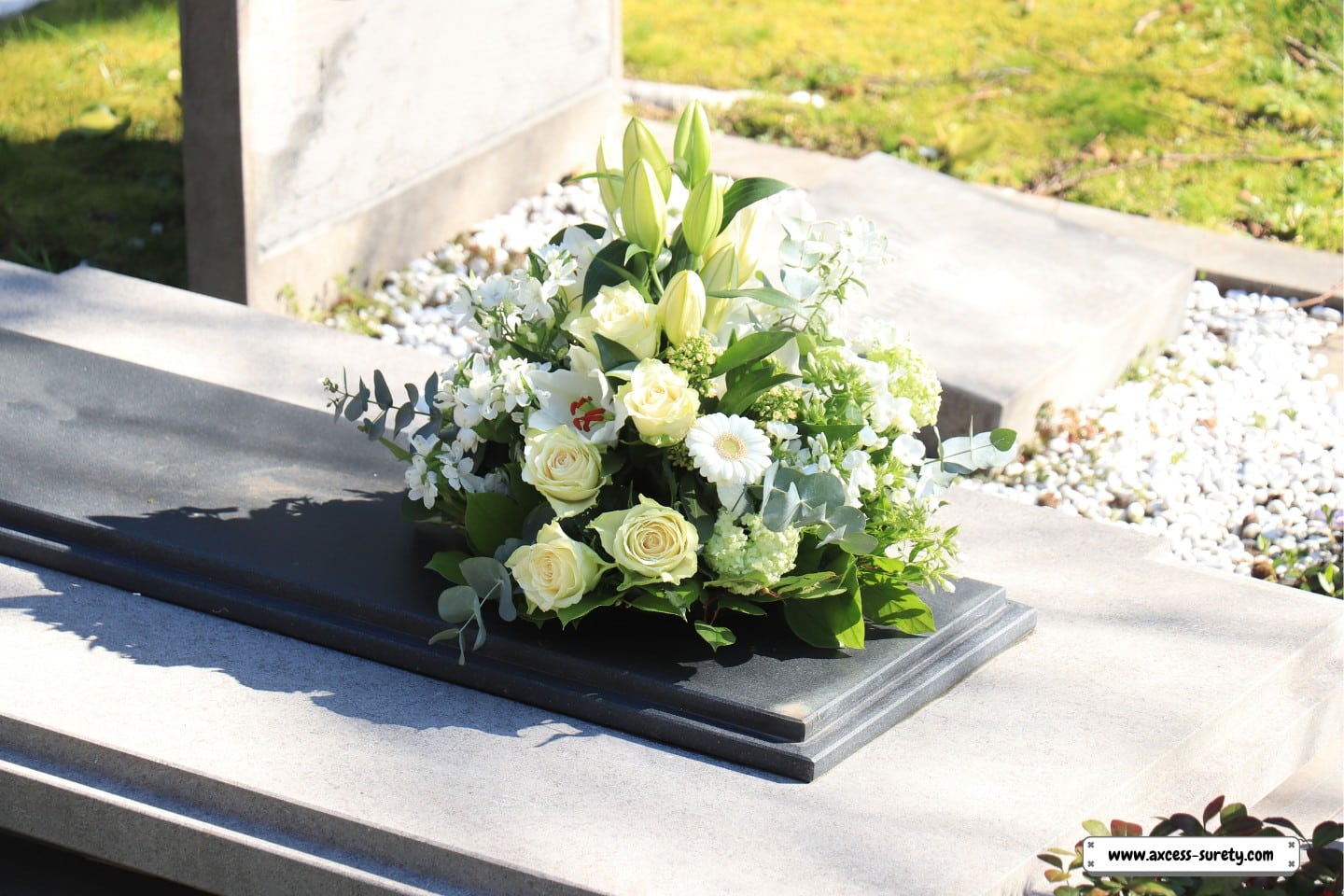 A grey marble tomb with white funeral flowers on it.