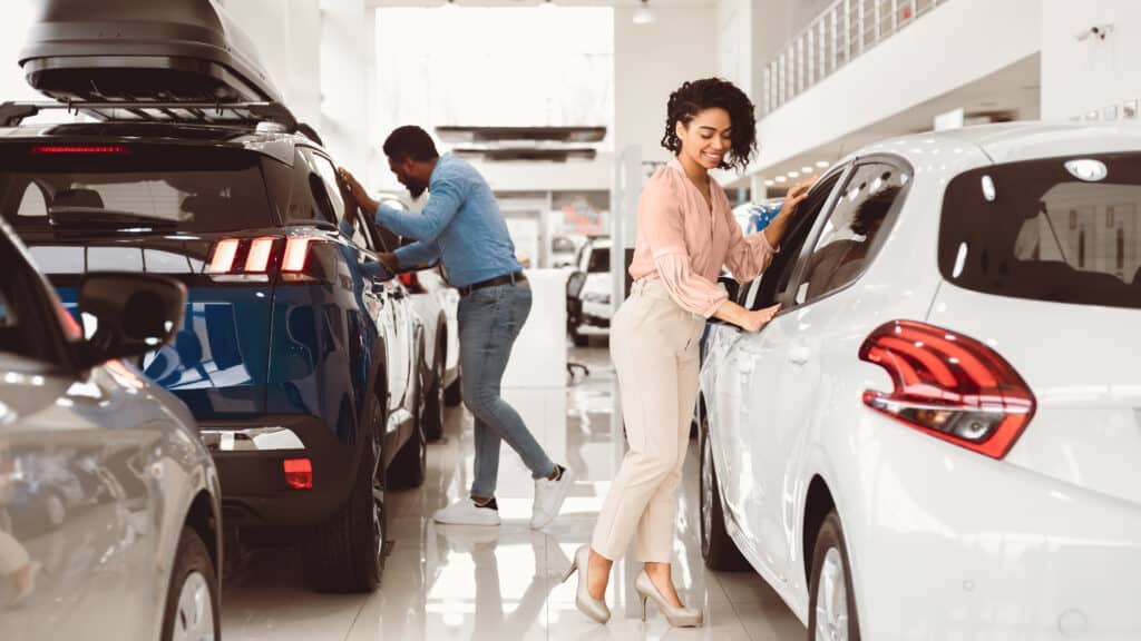 Couple Buying Car. African Spouses Choosing New Family Automobile In Luxury Dealership Store. Panorama