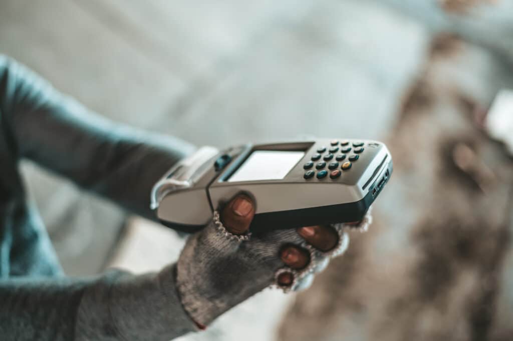Beggars sitting under the overpass with a credit card and credit card swipe machine.