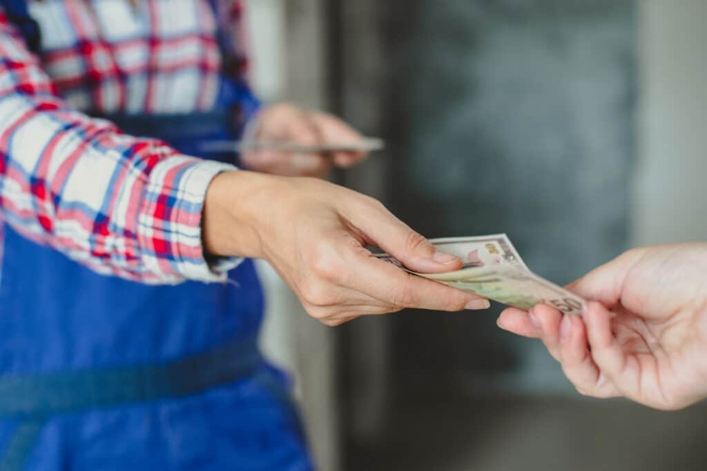 foreman hands wad of bills to woman construction worker. receiving salary for work