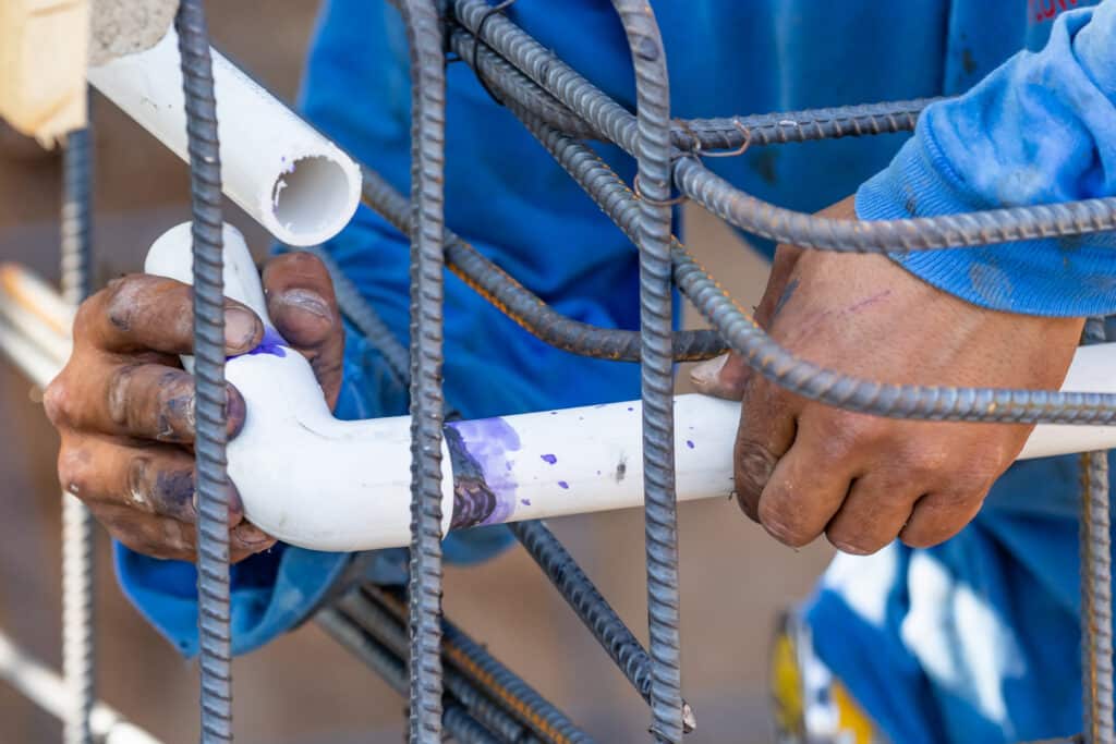 Plumber Installing PVC Pipe at Construction Site.
