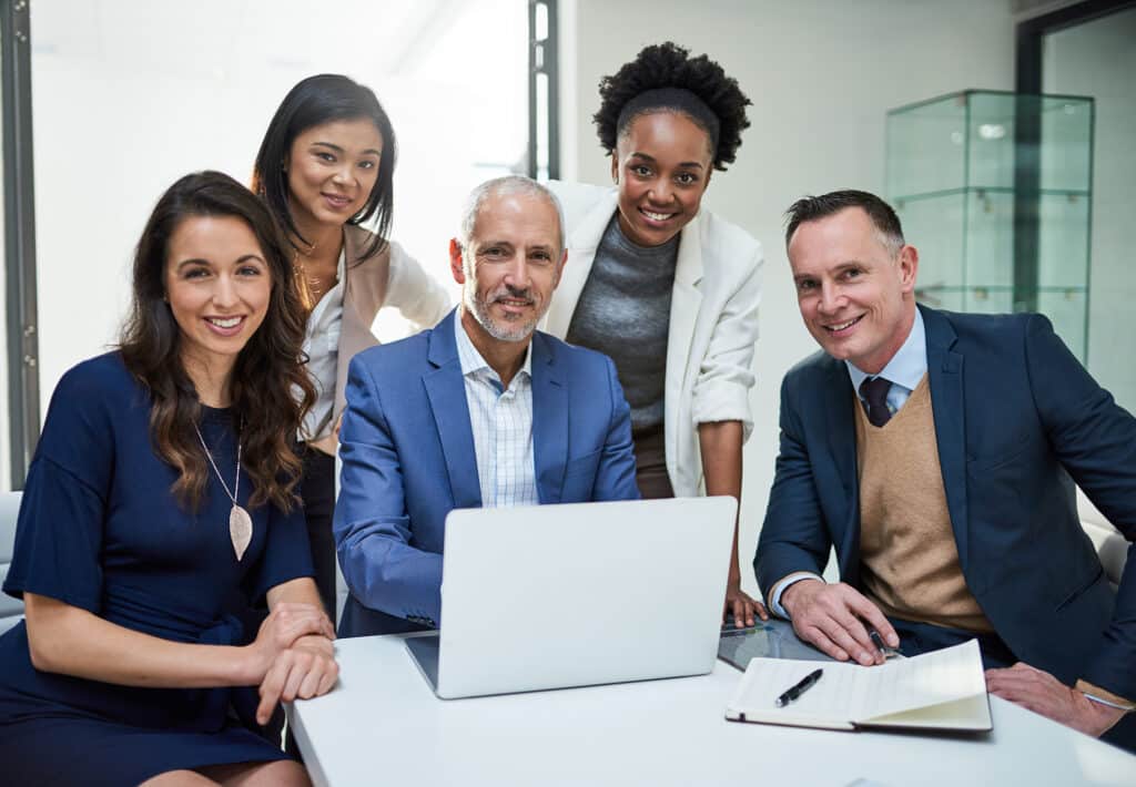 Portrait of a group of businesspeople working together on a laptop in a modern office.