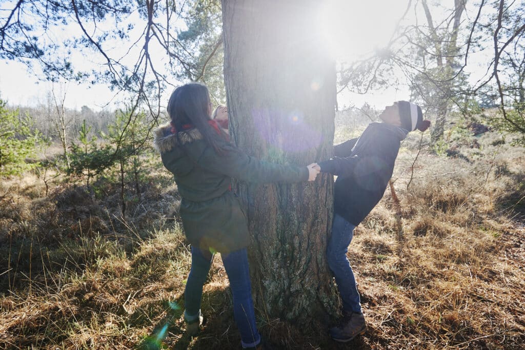 Siblings holding hands in ring around tree