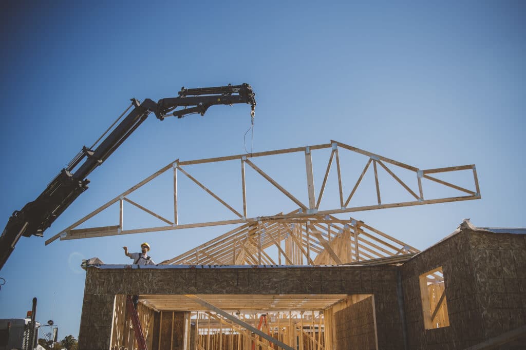 Builder directing crane positioning frame over building