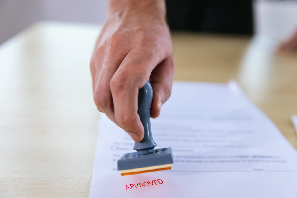 Business Man Stamping With Approved Stamp On Document. Business approve Stamp and certificate concept. Businessman Hands Stamping a document