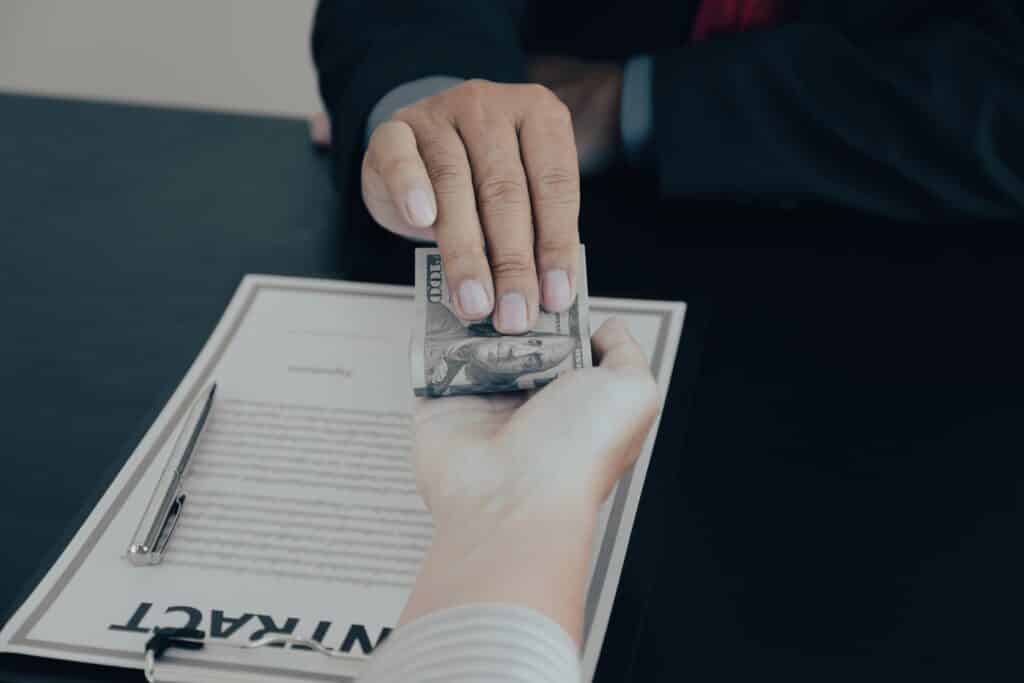 Businessman hand holding dollar bank note money to bribe financial officials or Boss is payout staff salary and anti-bribery.