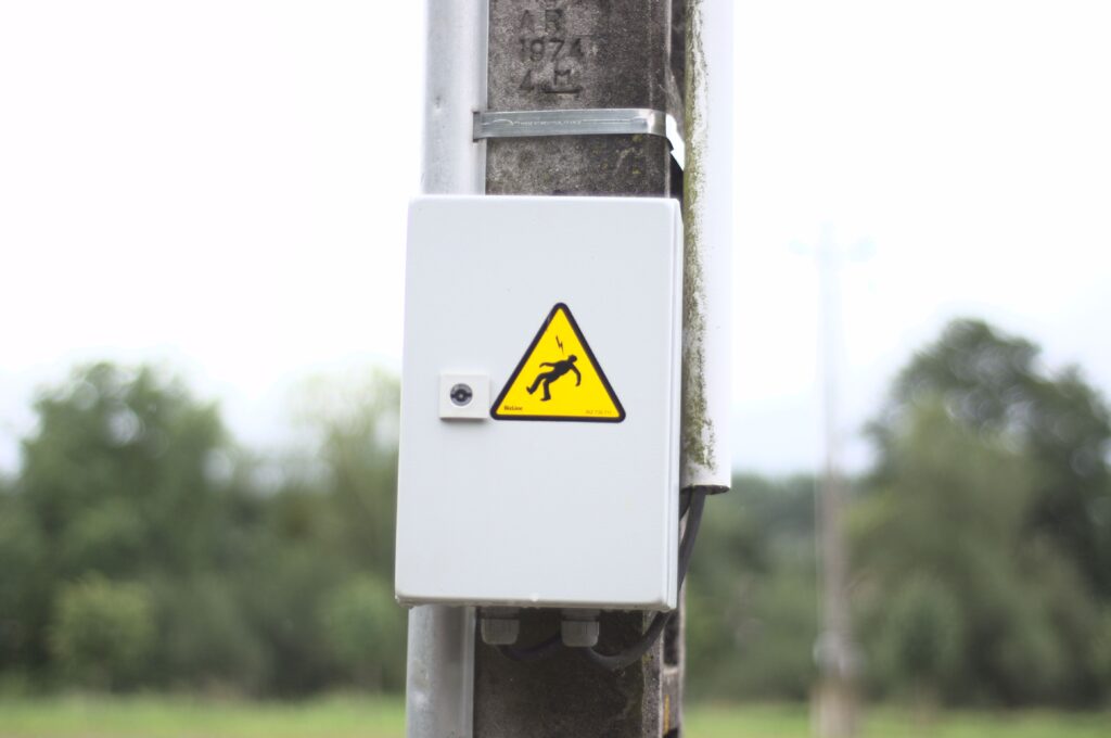 A closeup of a warning sign on an electric box with a yellow danger sign of being shocked