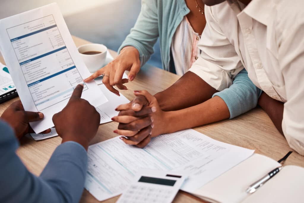 Couple holding hands, bank and application for loan, finance or mortgage to buy new home with docum.