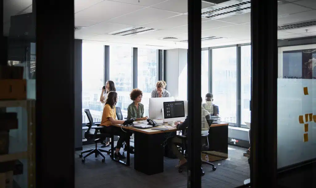 Creative business team working together in a casual office, seen through glass wall