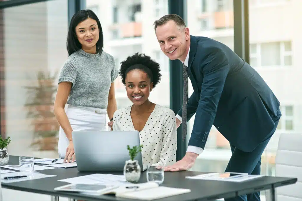 Cropped portrait of three businesspeople gathered around a laptop in the office.