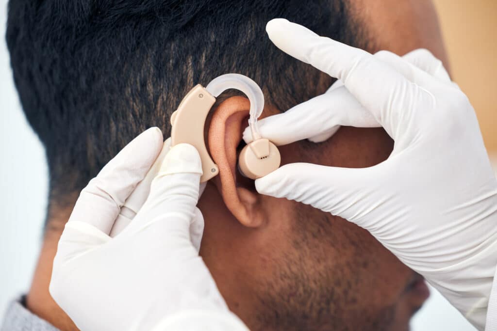 Hearing aid, man and doctor hands with patient consultation for ear and wellness at hospital. Help,.