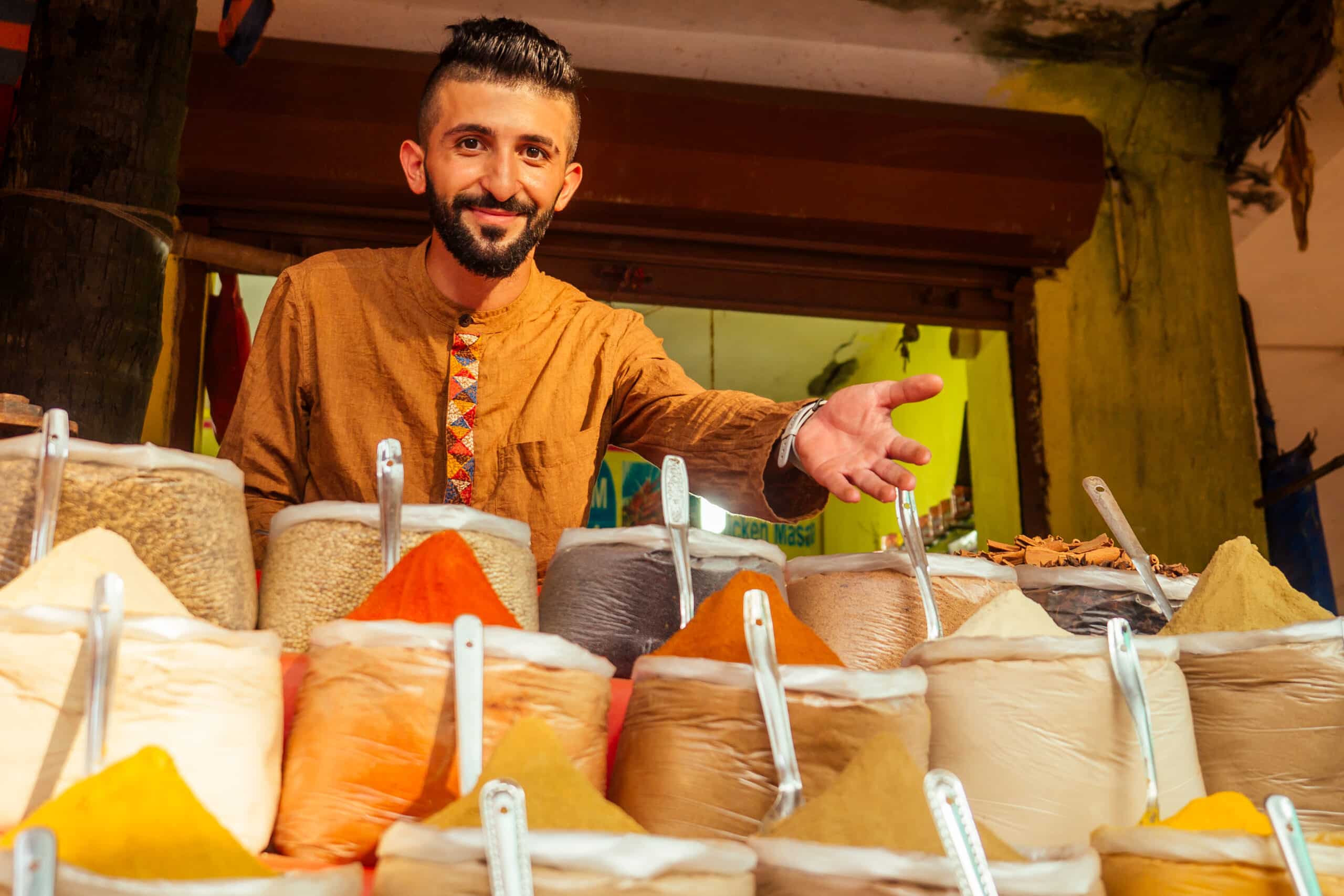 indian sallerman showing his small shop on arambol goa market.