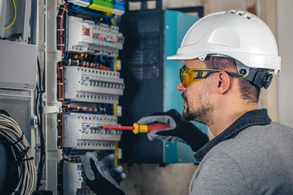Man, an electrical technician working in a switchboard with fuses. Installation and connection of electrical equipment.