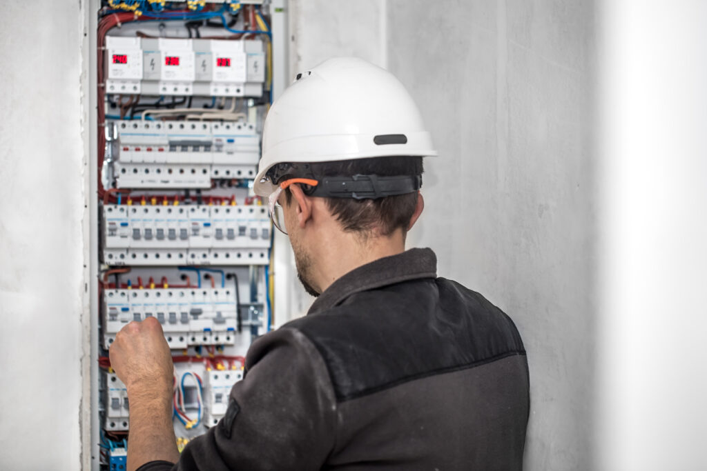 Man, an electrical technician working in a switchboard with fuses. Installation and connection of electrical equipment. Professional with tools in hand. concept of complex work, space for text. SSUCv3H4sIAAAAAAAEAI1Ru24DIRDsI+UfTtQ+yfheufxBikjprRQLrH3IGCweiSzL/x44TEQVpWNnltmdndvzU9MQBk5y8trcUhVrqVRw3oKXRkd4u3ngFrVAWyMopDdWgqpBBp4vGs4YQR2USvB9JYnz4INDl4Y9IA4ej1Ejg78SeaN9rptCrGT8ESnygeaikGwqxgWWmHfpOCoFGk1wpPD3zR9ib1oky8nJ/wXz47P4hiNqfl2tVZYtKoRseZ9byenboz3XR4AgpKn8fxkOKjV0ldLFSi71sfpm/LLmUb5xE7S3aQVSbBBlzAWYSmEcoiYWfAHnYrsoeDWIx1OYczVHG78aeKgSETNLJe129KXvh57SuZtfaE9JydnwkxS1xRz9IiNlrxUu0wYERjbBPHbtsJsPbc+GqWXTOLWHYTuNiDMVoo+Hv/8ATIEG57ECAAA=
