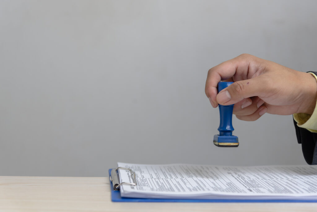 Man stamping approval of work finance banking or investment marketing documents on desk.