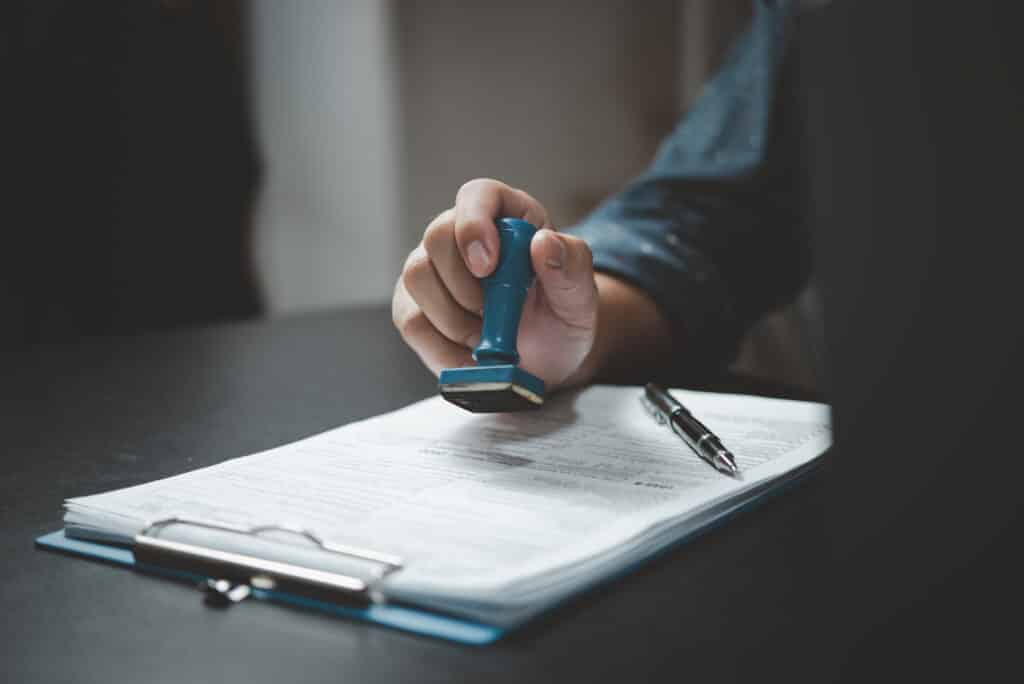Signing approval record documents stamp confirmation occupation signature. businessman hand stamping finance paper work concept.