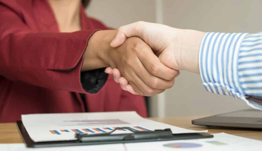 Two business leaders talk about charts, financial graphs showing results are analyzing and calculating planning strategies, business success building processes, and shake hands.